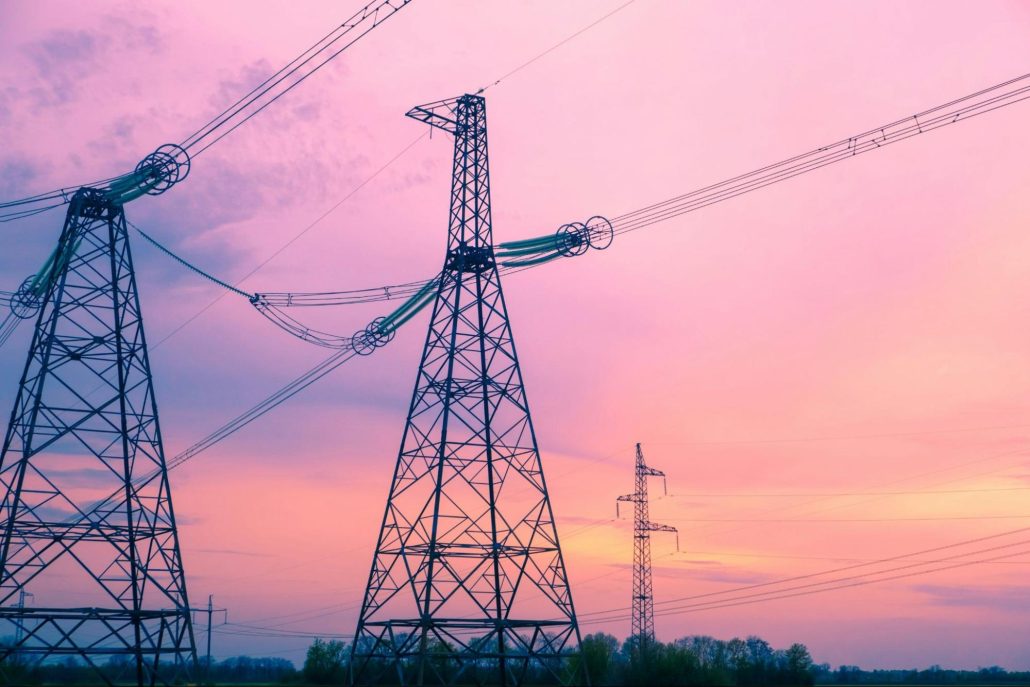  Electricity pylons silhouetted against a colorful sunset sky.