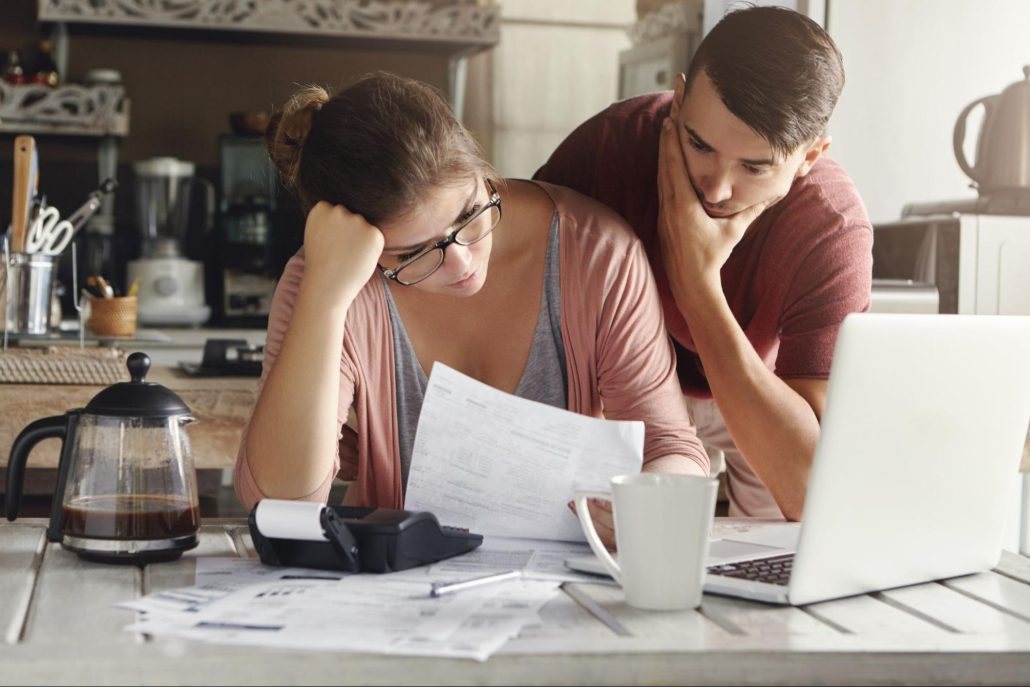  A man and woman are reviewing documents together at a table, focused on the paperwork in front of them.