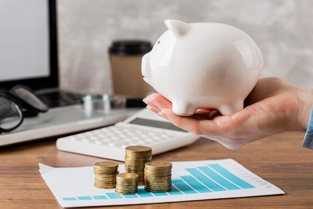 Hand holding piggy bank with growth chart and coins
